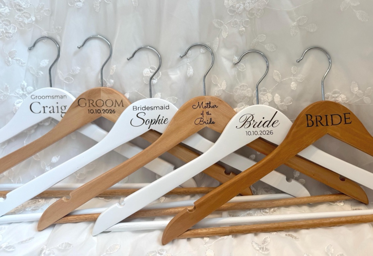 Six engraved hangers fanned out: Groomsman Craig, Groom, Bridesmaid Sophie, Mother of the Bride, Bride and BRIDE